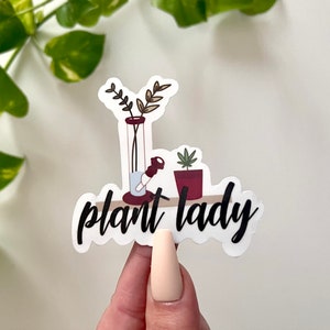 May include: White sticker with a black and white illustration of a bong, a potted plant, and the text "plant lady".