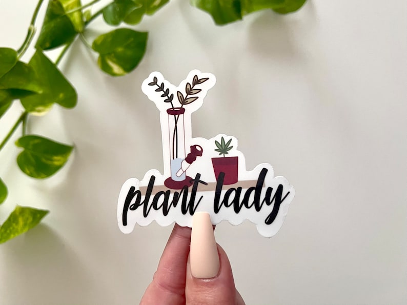 May include: White sticker with a black and white illustration of a bong, a potted plant, and the text "plant lady".