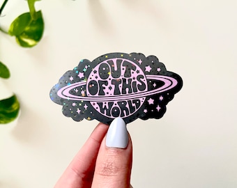 May include: A black and pink holographic sticker with a planet and the text "OUT OF THIS WORLD" in a retro font.