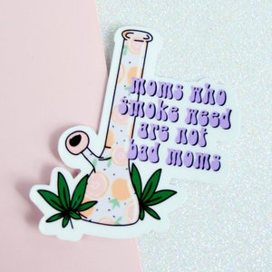 May include: A white sticker with a purple and orange bong design and the text "Moms who smoke weed are not bad moms".