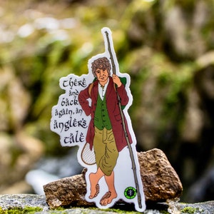 May include: A sticker featuring a cartoon illustration of a man with a beard and a walking stick. The text on the sticker reads "There and back again, an angler's tale."