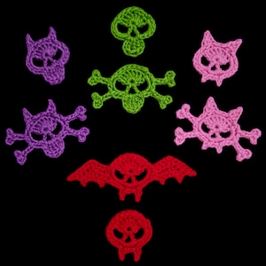 Könnte beinhalten: Eine Sammlung gehäkelter Schädel- und Fledermaus-Applikationen in verschiedenen Farben, darunter Lila, Grün und Rot. Die Applikationen sind auf schwarzem Hintergrund angeordnet. Die Schädeldesigns variieren, einige mit Totenknochen, andere mit fledermausartigen Merkmalen.
