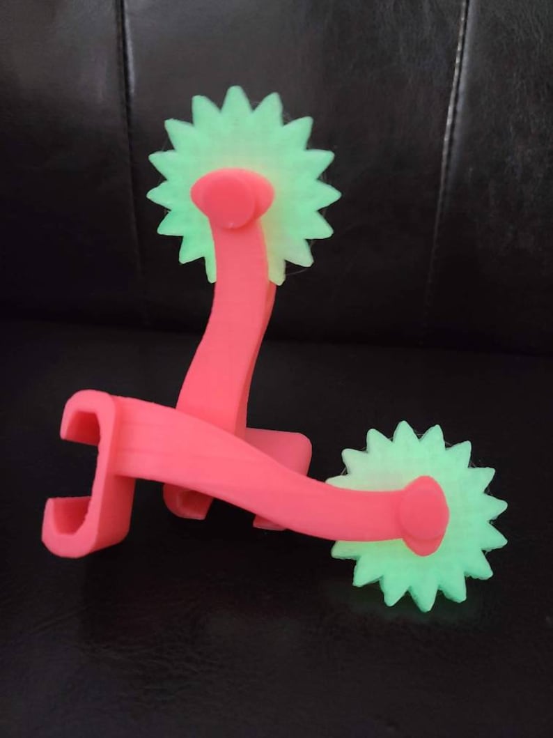 May include: Two pink plastic rolling tools with green star-shaped wheels. The tools are designed for crafting and creating patterns in clay or dough.