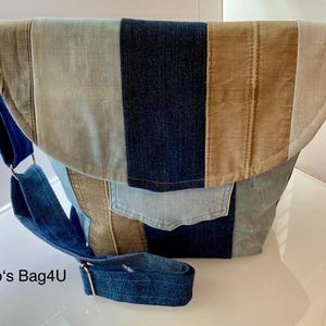 Könnte beinhalten: Eine blaue, braune und hellblaue Denim-Patchwork-Umhängetasche mit einem langen verstellbaren Riemen. Die Tasche hat einen Klappenverschluss und eine große Tasche auf der Vorderseite. Der Text "Karo's Bag4U" ist in der linken unteren Ecke des Bildes sichtbar.