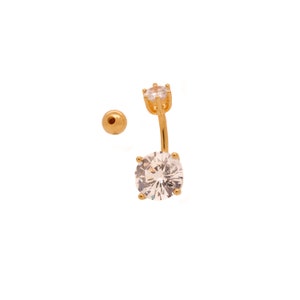 May include: Gold belly button ring with two clear round cubic zirconia stones.