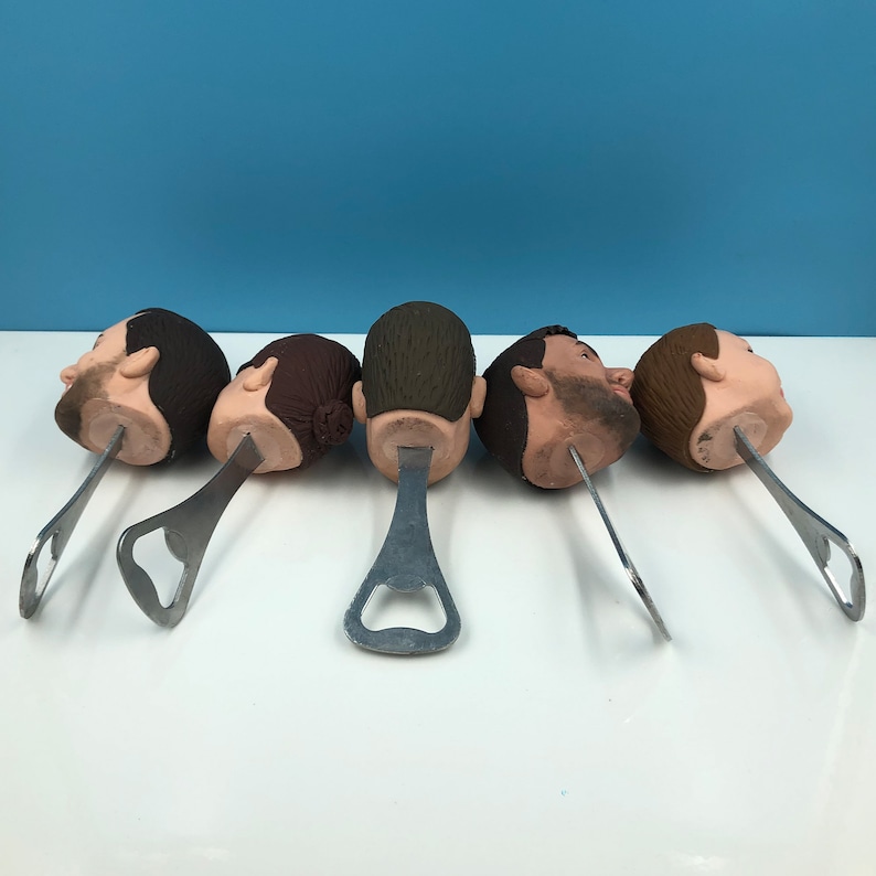 May include: Five bottle openers with different sculpted human heads. Each opener is made of metal and has a classic bottle opener design.