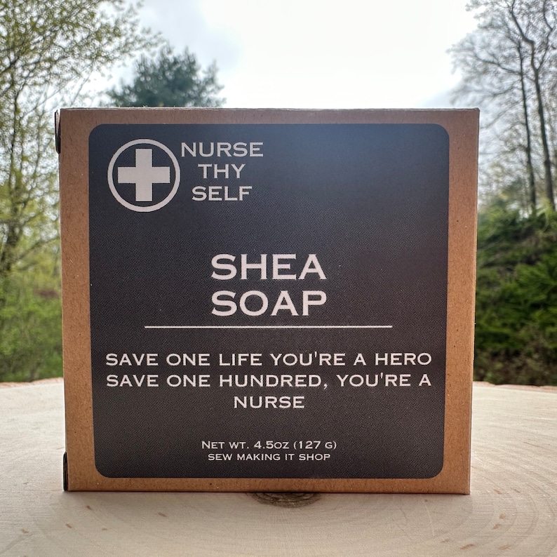 May include: A brown cardboard box with a white cross and the text "Nurse Thy Self" on the front. The box also has the text "Shea Soap" and the slogan "Save one life you're a hero, save one hundred, you're a nurse". The box also includes the text "Net Wt. 4.5oz (127g) Sew Making It Shop".
