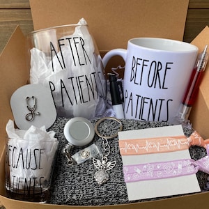 Puede incluir: Una caja de regalo llena de artículos para una enfermera. La caja contiene una copa de vino, una taza, un vaso de chupito, un llavero, un portagajes retráctil, un par de cintas para el pelo y una bufanda gris. La copa de vino, la taza y el vaso de chupito tienen todos el texto "Después de los pacientes", "Antes de los pacientes" y "Porque los pacientes" impreso en ellos.