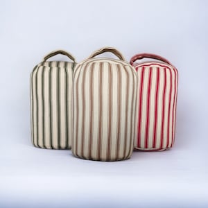 May include: Three striped doorstops in different colours. The doorstop on the left is green and white, the middle doorstop is brown and white, and the doorstop on the right is red and white.