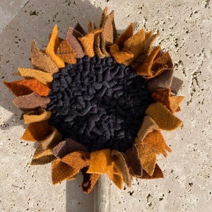 May include: A brown, orange, and black felt sunflower with a wooden stem.