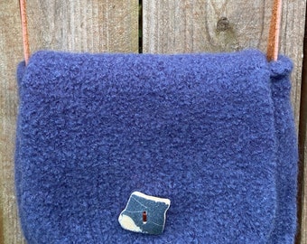 May include: A small, blue, fuzzy crossbody bag with a leather strap and a decorative stone accent.
