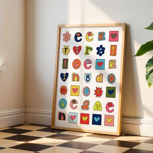 May include: A framed print with a white background and colourful letters spelling out "seek first the good cave". Each letter is surrounded by a colourful border and some letters have a small flower, heart, or star design.