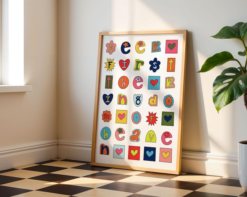 May include: A framed print with a white background and colourful letters spelling out "seek first the good cave". Each letter is surrounded by a colourful border and some letters have a small flower, heart, or star design.
