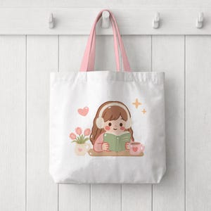 May include: A white tote bag with pink handles featuring a graphic illustration of a person with brown hair wearing white headphones, reading a green book, accompanied by a small vase of pink tulips, a pink mug, a pink heart, and two yellow stars.