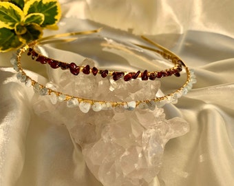 May include: A gold headband with two rows of wire-wrapped gemstones. The top row features small, dark red gemstones, while the bottom row features light blue gemstones.