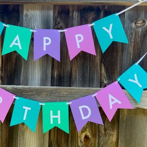 May include: A banner with the words "Happy Birthday" in white letters on alternating pink, purple, and teal triangular flags.