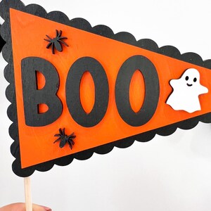 May include: Orange and black Halloween pennant with the word "BOO" in black letters, two black spiders, and a white ghost with a smiling face.