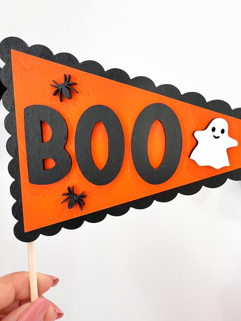 May include: Orange and black Halloween pennant with the word "BOO" in black letters, two black spiders, and a white ghost with a smiling face.