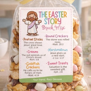 以下が含まれることがあります： イースターのスナックミックスが入った透明な袋で、黄色のリボンで結ばれています。「The Easter Story Snack Mix」と書かれたラベルには、イエス・キリストのイラストが描かれています。プレッツェル、クラッカー、クランベリー、金魚クラッカー、マシュマロ、お菓子が含まれています。
