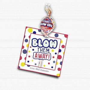 Puede incluir: Una tarjeta roja, blanca y azul con lunares y el texto "Blow Them Away!"  Love, Miss Anderson. Una piruleta roja y blanca con el texto "Blow Pop Cherry" está unida a la tarjeta.