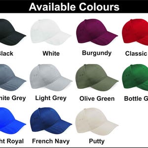 May include: A selection of baseball caps in a range of colours: black, white, burgundy, and red. Other colours include graphite grey, light grey, olive green, bottle green, bright royal, french navy, and putty. The text "Available Colours" is at the top.