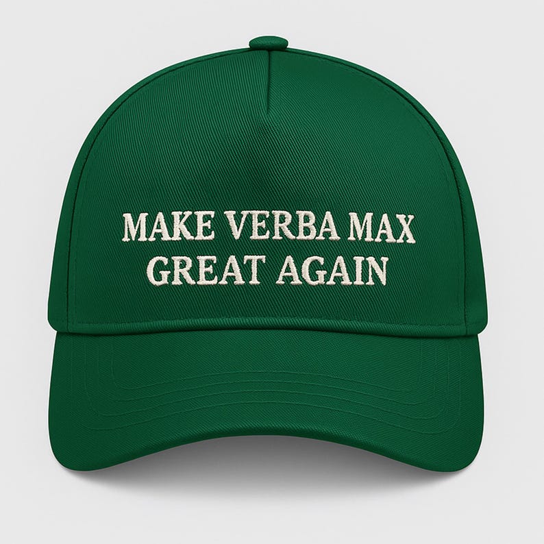 May include: A green baseball cap with the embroidered text "MAKE VERBA MAX GREAT AGAIN" in white. The cap has a curved peak and a button on top. The hat is a solid, vibrant green colour.