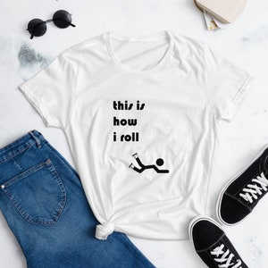 Puede incluir: Camiseta blanca con texto negro que dice "this is how i roll" y un figurín sobre patines que se cae.