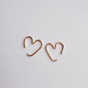 May include: A pair of gold heart-shaped hoop earrings. The earrings are simple and delicate, and would make a great gift for a loved one.