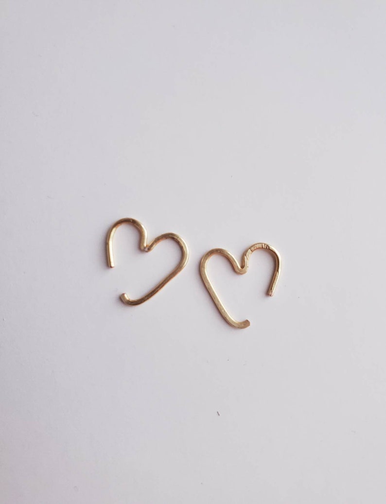 May include: A pair of gold heart-shaped hoop earrings. The earrings are simple and delicate, and would make a great gift for a loved one.