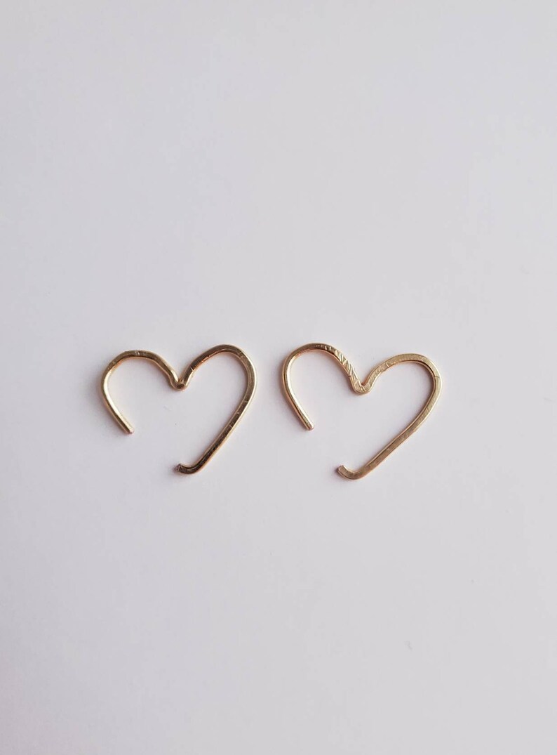 May include: A pair of gold heart-shaped hoop earrings. The earrings are simple and delicate, and would make a great gift for a loved one.