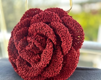 May include: A red crocheted rose-shaped handbag with a gold metal handle.