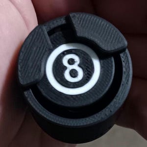 May include: Black and white 8-ball pool cue tip with a textured surface.