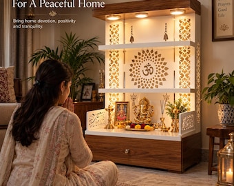 May include: A wooden home temple unit featuring a white back panel with a laser-cut Om symbol, integrated LED lighting, three shelves, and a storage drawer. The structure includes decorative side panels and hanging brass bells for display.