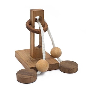 Op de afbeelding: Houten puzzel met een touw en drie houten ballen. Het touw wordt door een ring en een gat in een houten paal geleid. De ballen zijn aan het touw bevestigd.
