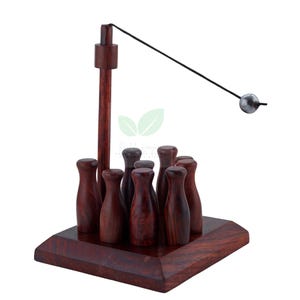 Può includere: Un gioco da bowling da scrivania in legno con finitura scura. Il set include nove piccoli birilli, una base in legno, un palo verticale e una palla di metallo oscillante su una corda. Il gioco è progettato per il gioco da tavolo.