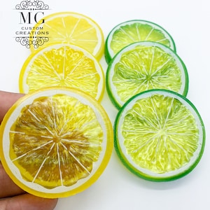 May include: A set of six lemon and lime slices, each with a glossy finish and a white rim. The lemon slices are yellow and the lime slices are green.