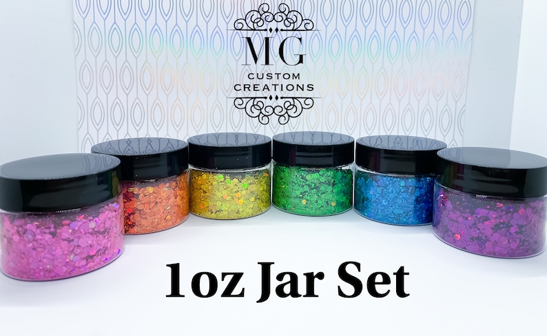 May include: Set of six 1 oz jars filled with colorful glitter. The jars have black lids and are arranged in a row. The text "1 oz Jar Set" is printed below the jars.