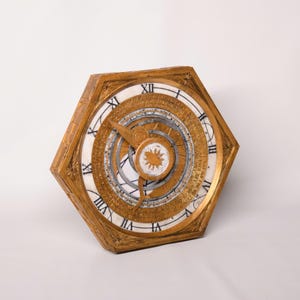 May include: A gold-toned hexagonal compass with a white face and black Roman numeral markings. The compass has a rotating needle and a detailed map of the world.
