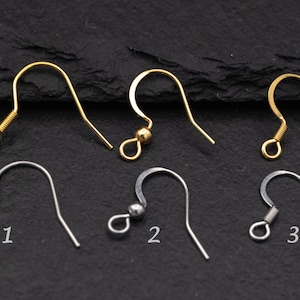May include: An assortment of earring hooks in gold and silver tones. The hooks vary in design, including those with coiled springs, small beads, and simple curved shapes. The image is a close-up shot, showcasing the details of each hook.