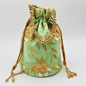 Może przedstawiać: Zielona torebka ze sznurkiem do ściągania, haftem złotym i ozdobnymi koralikami. Torebka ma kwiatowy wzór i idealnie nadaje się do noszenia drobnych przedmiotów.