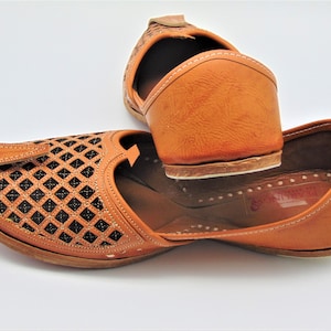 May include: A pair of brown leather shoes with intricate cut-out designs. The shoes have a pointed toe and a closed back. The shoes are made of a soft, supple leather and have a comfortable fit.