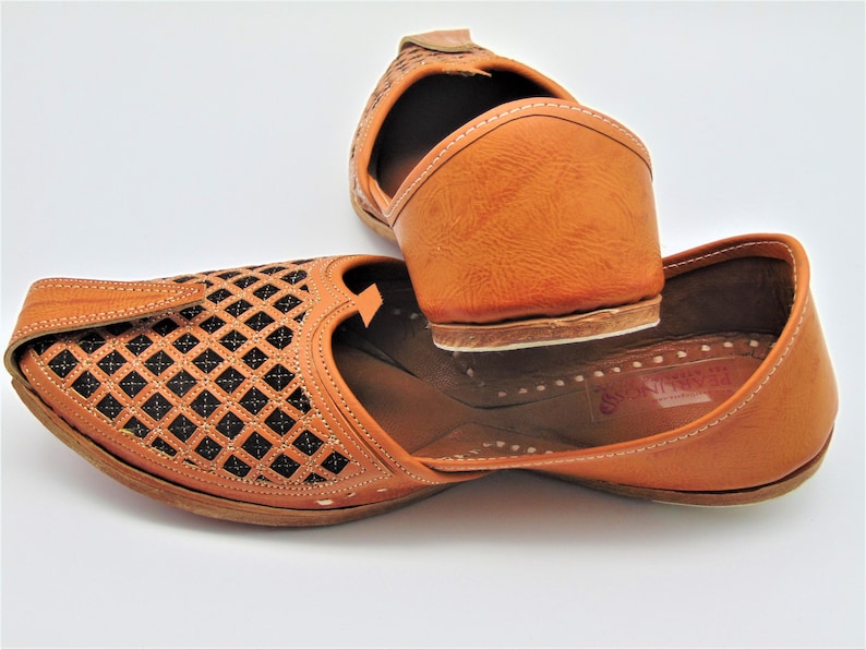 May include: A pair of brown leather shoes with intricate cut-out designs. The shoes have a pointed toe and a closed back. The shoes are made of a soft, supple leather and have a comfortable fit.