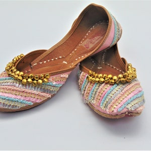 May include: A pair of pink and gold embroidered flat shoes with a decorative beaded trim. The shoes have a pointed toe and a low heel.