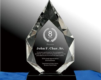 Op de afbeelding: Een heldere kristallen prijs met een zwarte basis. De prijs heeft een diamantvorm met een zwart middenpaneel. Tekst op het paneel luidt "8 YEARS" en "John F. Char, Sr.". De prijs is voor leiderschap.