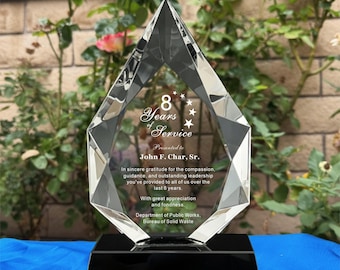 Op de afbeelding: Een heldere kristallen award met een zwarte basis. De award heeft de vorm van een diamant en bevat de tekst "8 Years of Service" en een toewijding aan John F. Char, Sr. De award wordt uitgereikt door het Department of Public Works.