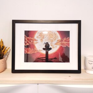May include: Framed print of a black and white illustration of a figure standing on a platform with a large red moon in the background. The moon has a textured surface and is surrounded by clouds.