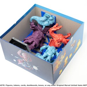 May include: A blue box with a cardboard insert for storing miniature figures. The box has a printed image of a superhero with a blue and red color scheme. The insert has slots for five figures, including a purple figure, a blue figure, a red figure, and two blue figures.