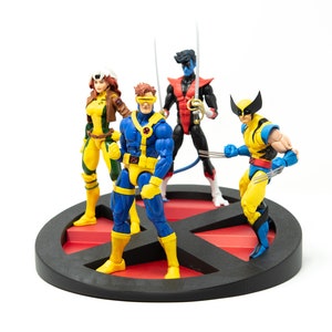 May include: A set of four action figures of X-Men characters, including Wolverine, Cyclops, Rogue, and Nightcrawler. The figures are posed in a dynamic action stance and are standing on a black and red X-Men logo base.