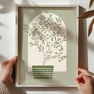 Peut inclure: Une affiche encadrée représentant un olivier dans un pot vert, sur un fond vert clair et crème. L'olivier a des feuilles et des olives vertes. Le cadre est de couleur bois clair.