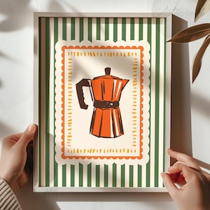 Könnte beinhalten: Gerahmter Druck mit einer Retro-Illustration einer orangefarbenen Espressokanne. Das Kunstwerk befindet sich vor einem cremefarbenen Hintergrund mit einem orangefarbenen, gewellten Rand und einem grün-weiß gestreiften Hintergrund. Der Rahmen ist aus hellem Holz.